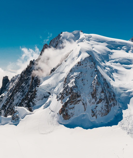 Snødekte fjelltopper med skarpe kanter og en klar blå himmel.