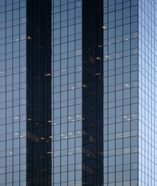 Nærbilde av en moderne glassbygning med refleksjoner av himmelen og bylandskapet.