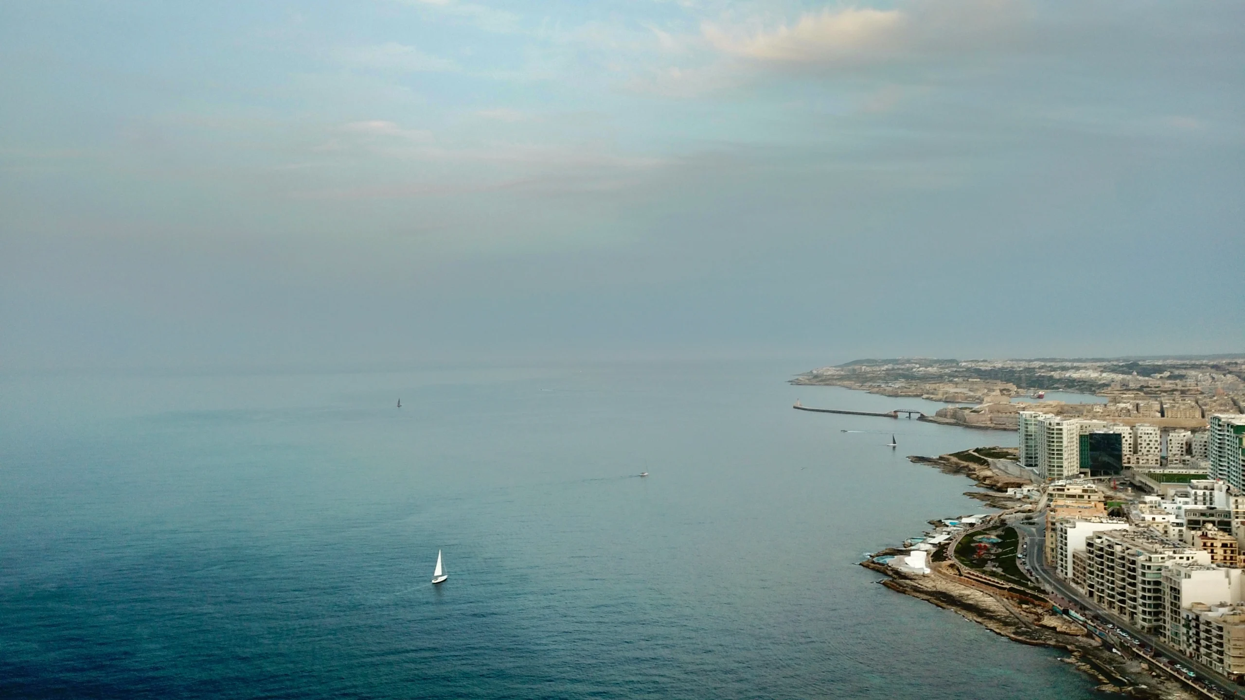 Luftfoto av Mediterranean kystlinje med seilbåter og moderne bygninger