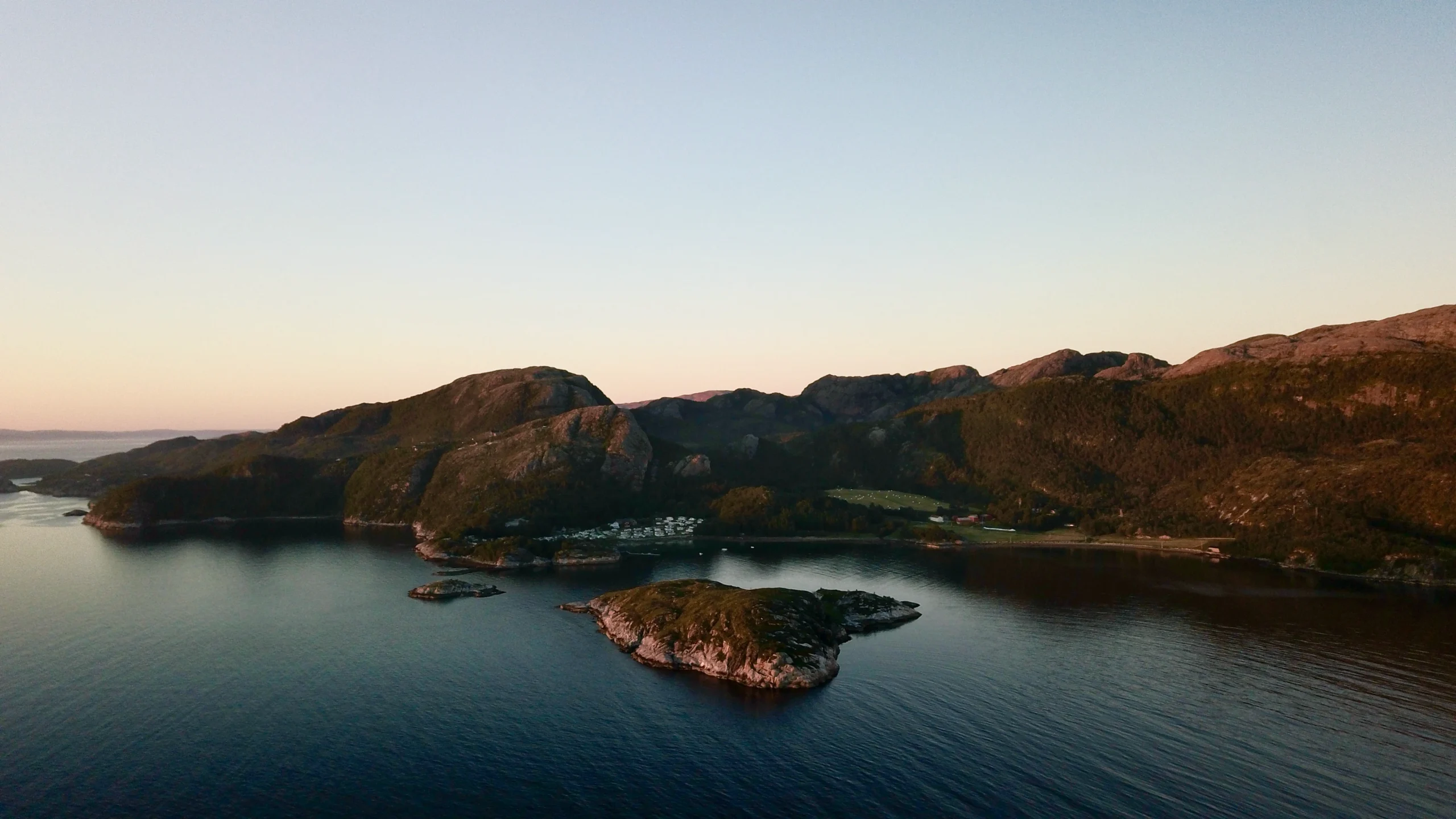 Luftfoto av norsk fjordlandskap med øyer og fjell i solnedgang